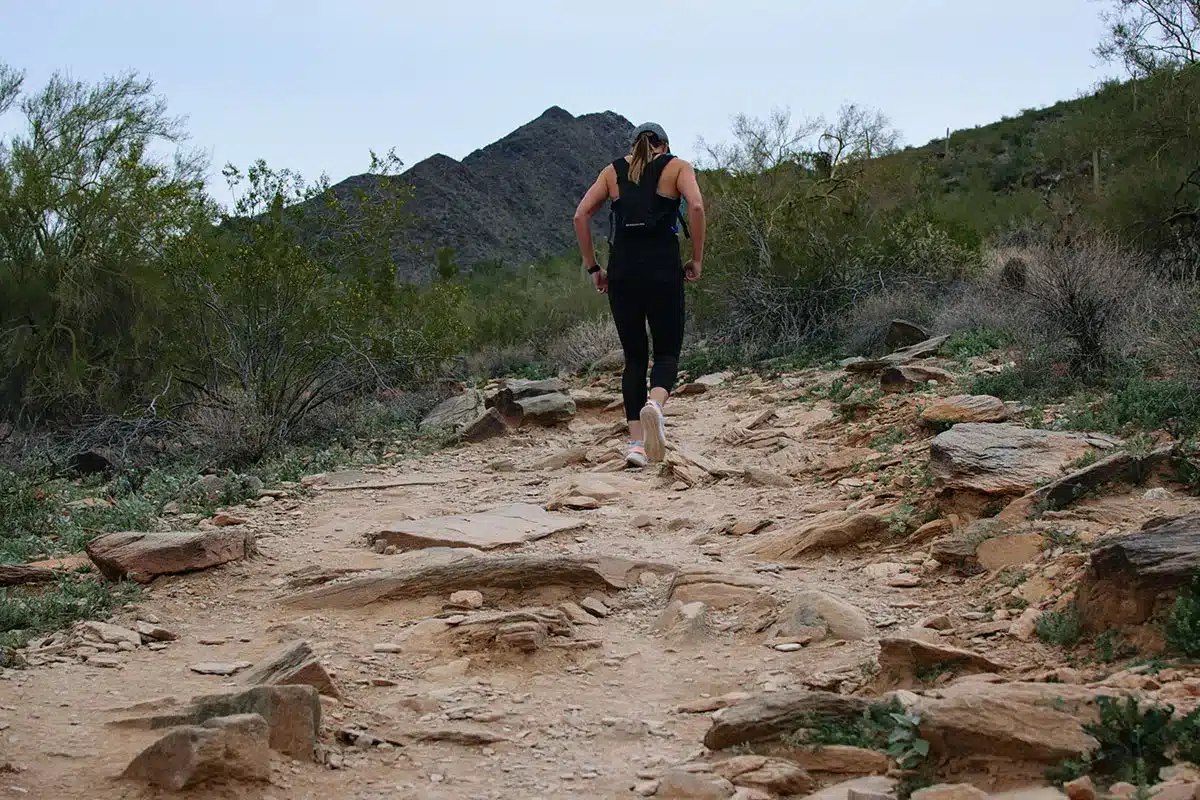Woman trail running in desert landscape.
