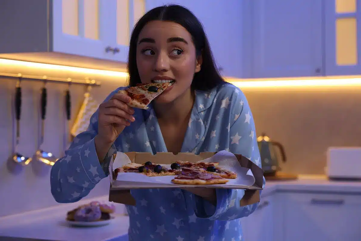 Woman eating pizza late at night.