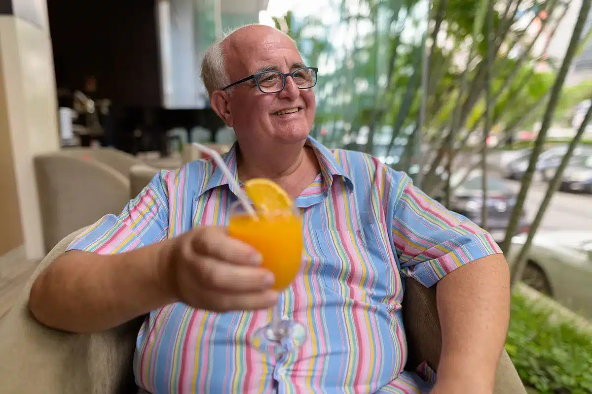 Smiling older man enjoying a glass of orange juice.