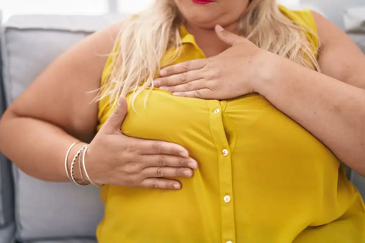 Plus-size woman holding her chest area.