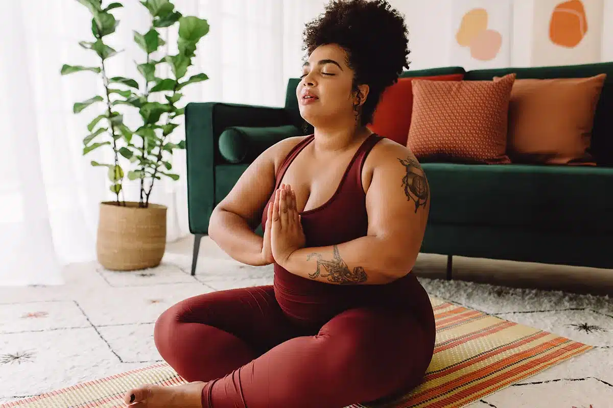 Plus-size woman meditating in lotus position.