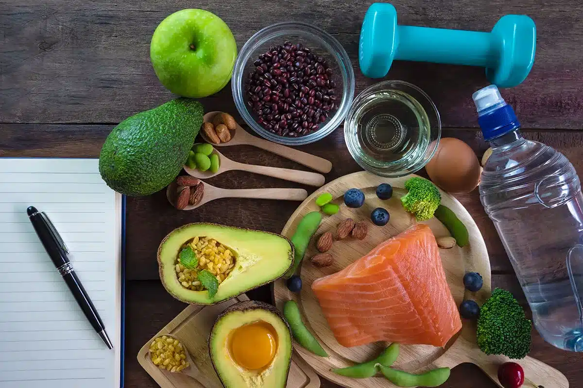 Salmon, avocado, and other healthy foods with dumbbells.