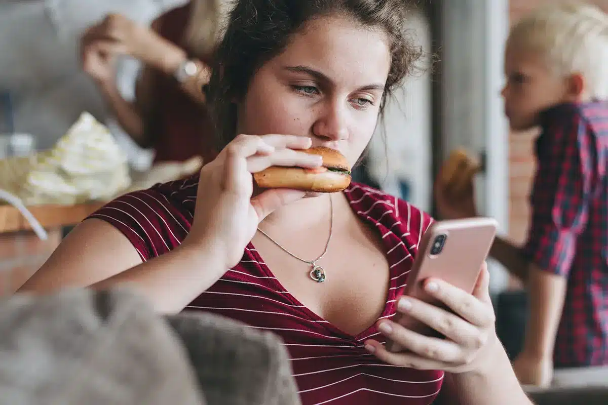 Teenager eating and using phone.