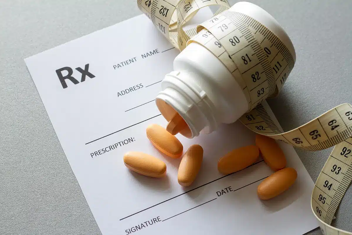Prescription bottle and pills with measuring tape.