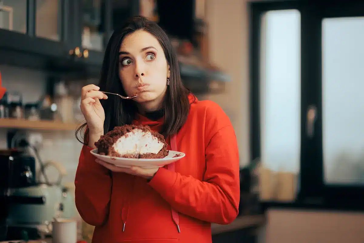 Woman enjoying a large piece of cake.
