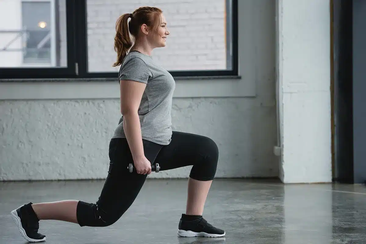 Woman doing lunges with dumbbells.
