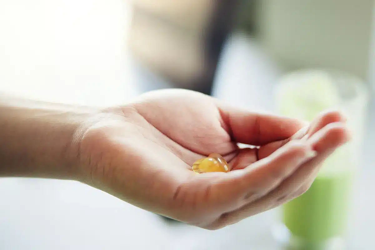 Hand holding a supplement capsule.