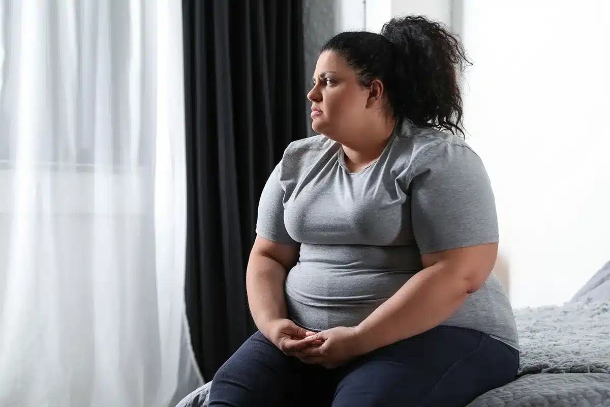 Woman sitting pensively by window.