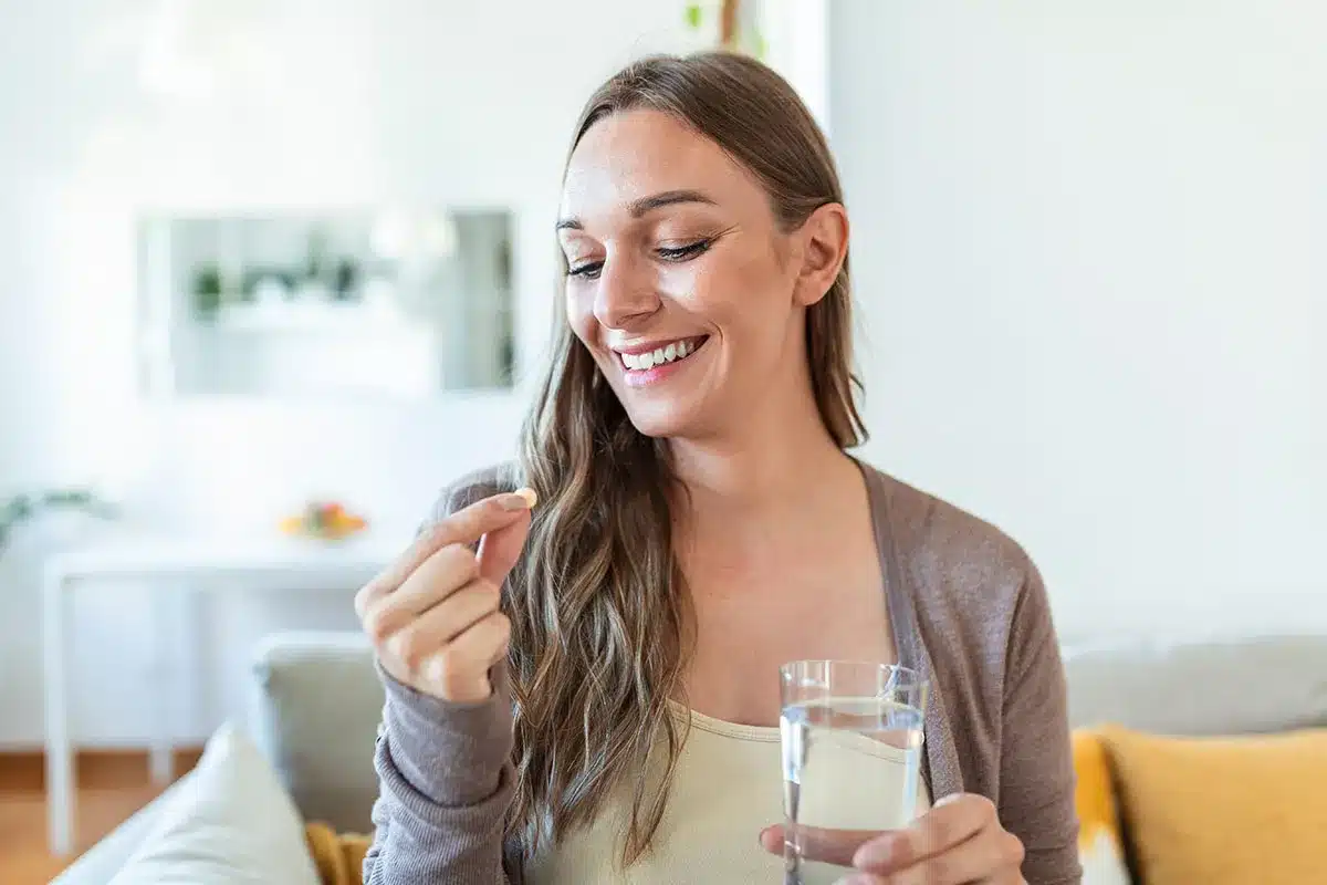 Woman taking a pill with water.