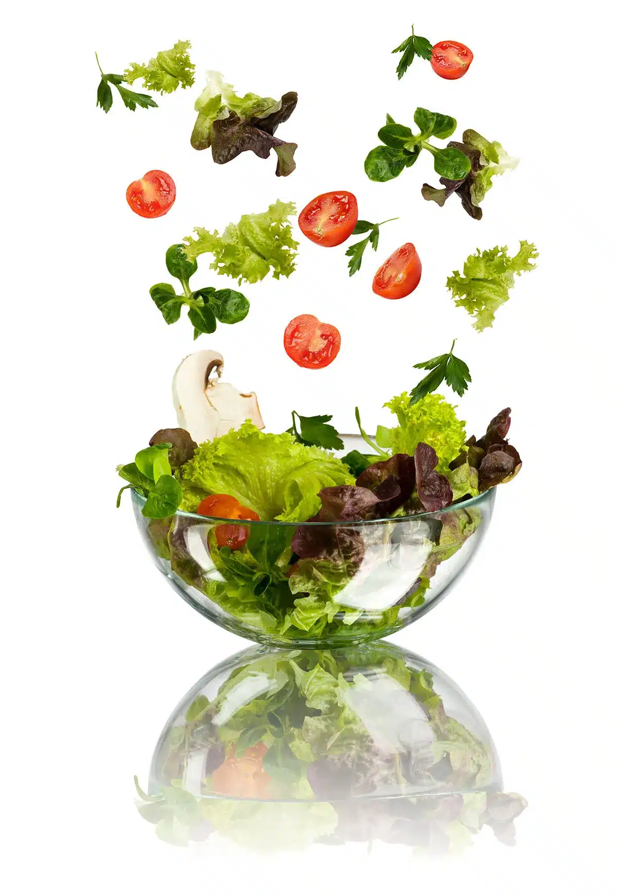 Salad ingredients falling into a bowl.