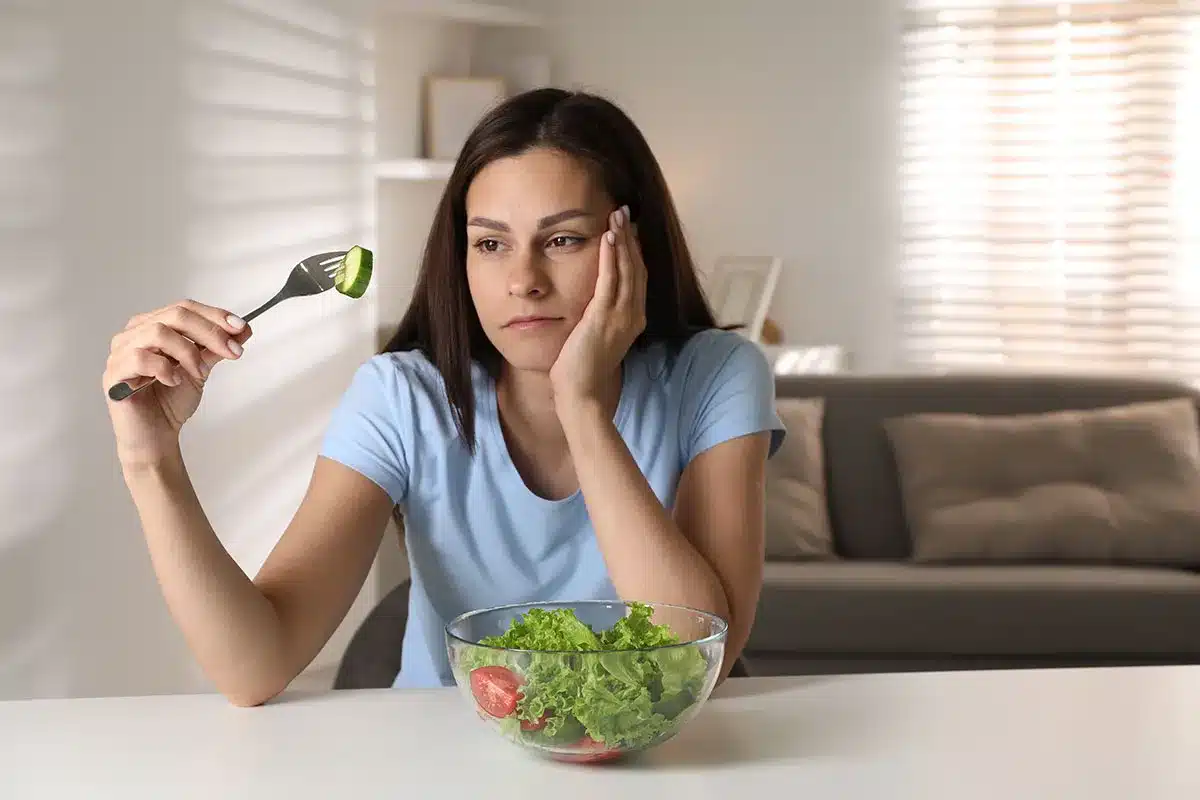 Woman looking unhappy at a salad.