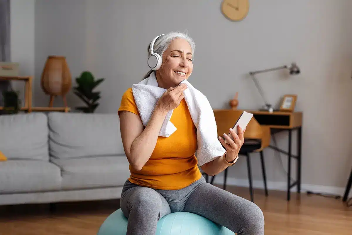 Senior woman exercising with phone and headphones.