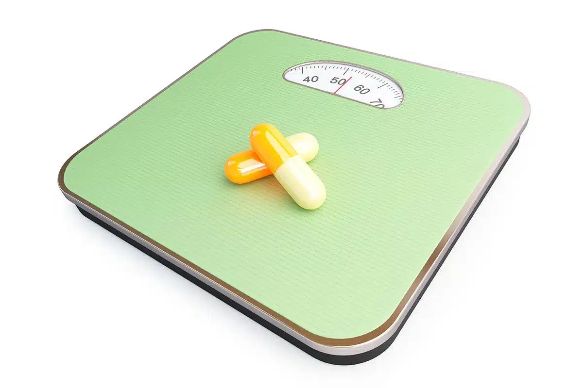 Weight loss pills on scale.