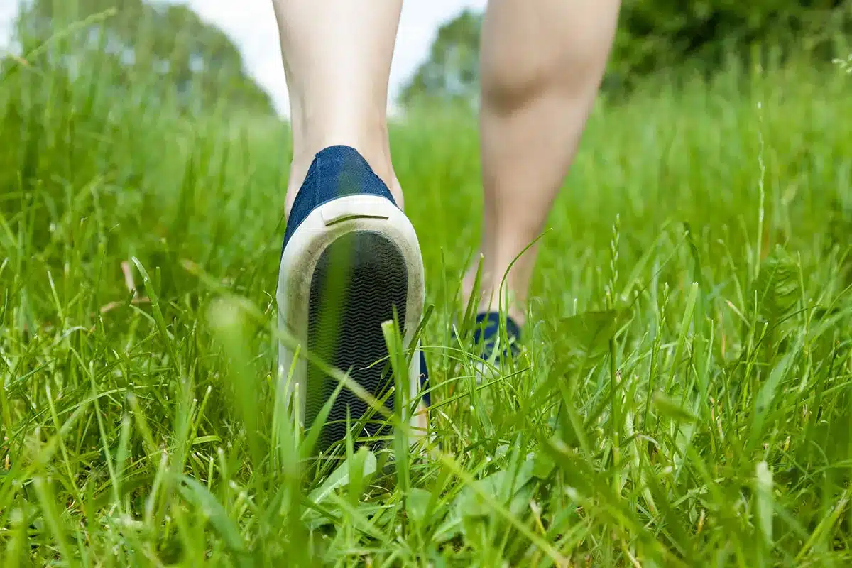 Feet walking in green grass.