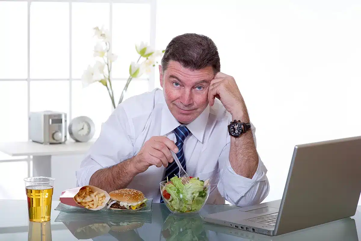 Businessman choosing between salad and burger.