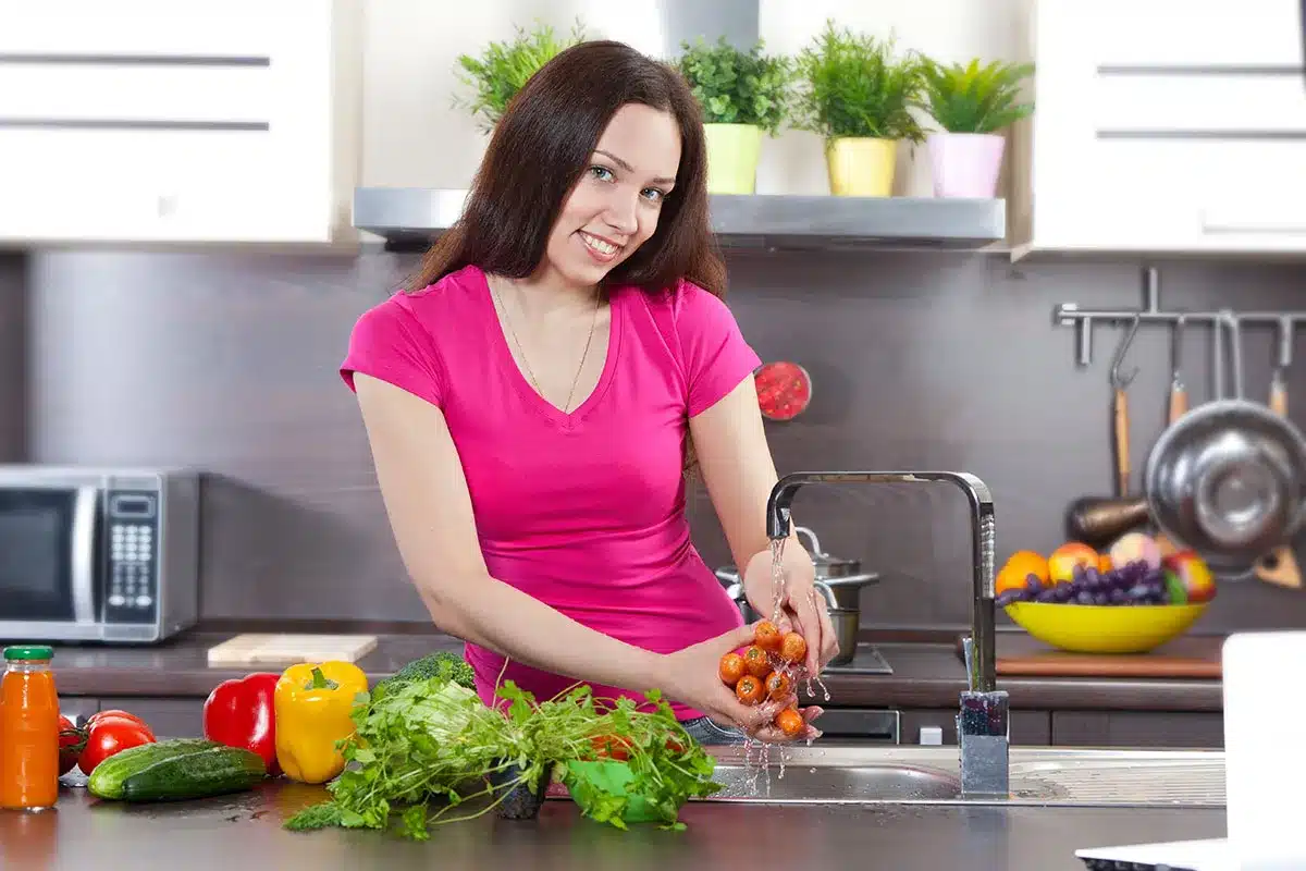 Woman washing vegetables in kitchen.