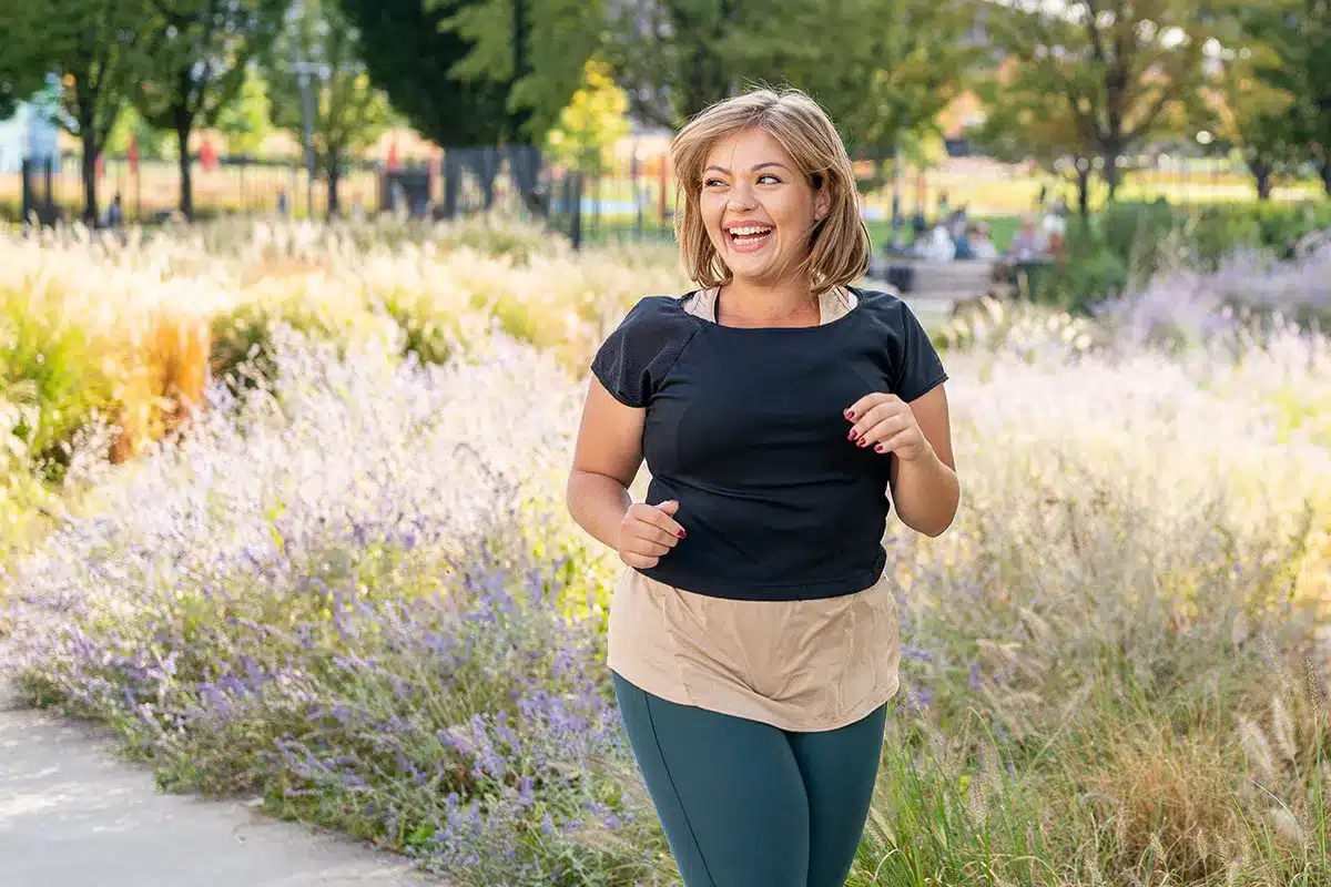 Happy plus-size woman jogging outdoors.