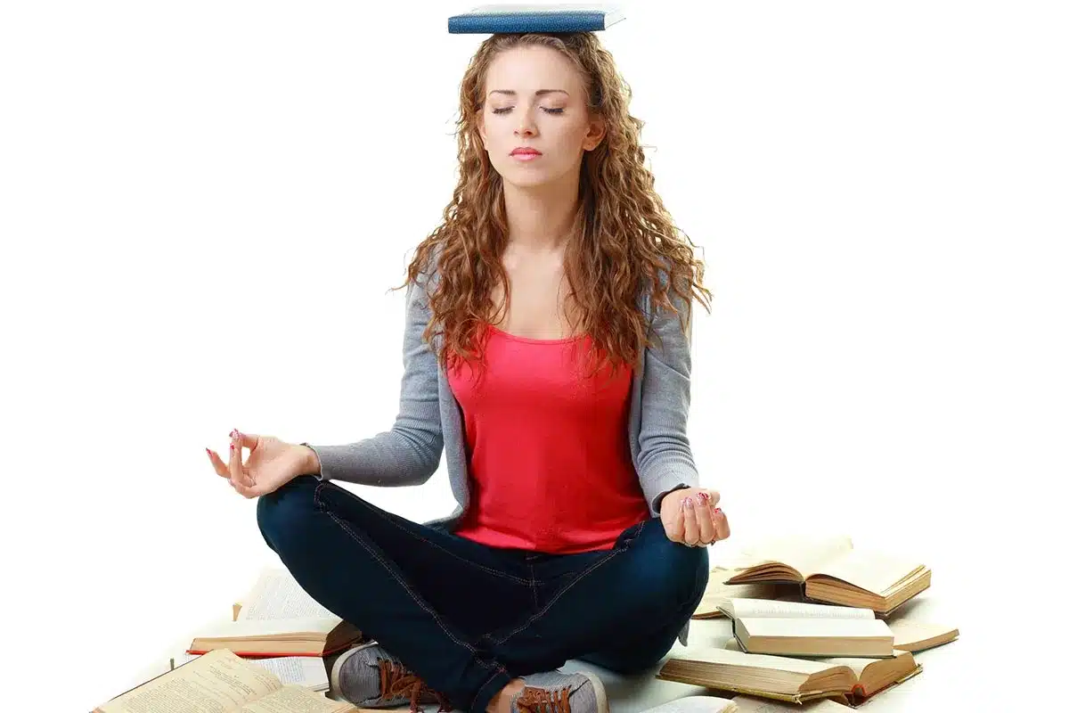 Student meditating amidst books.