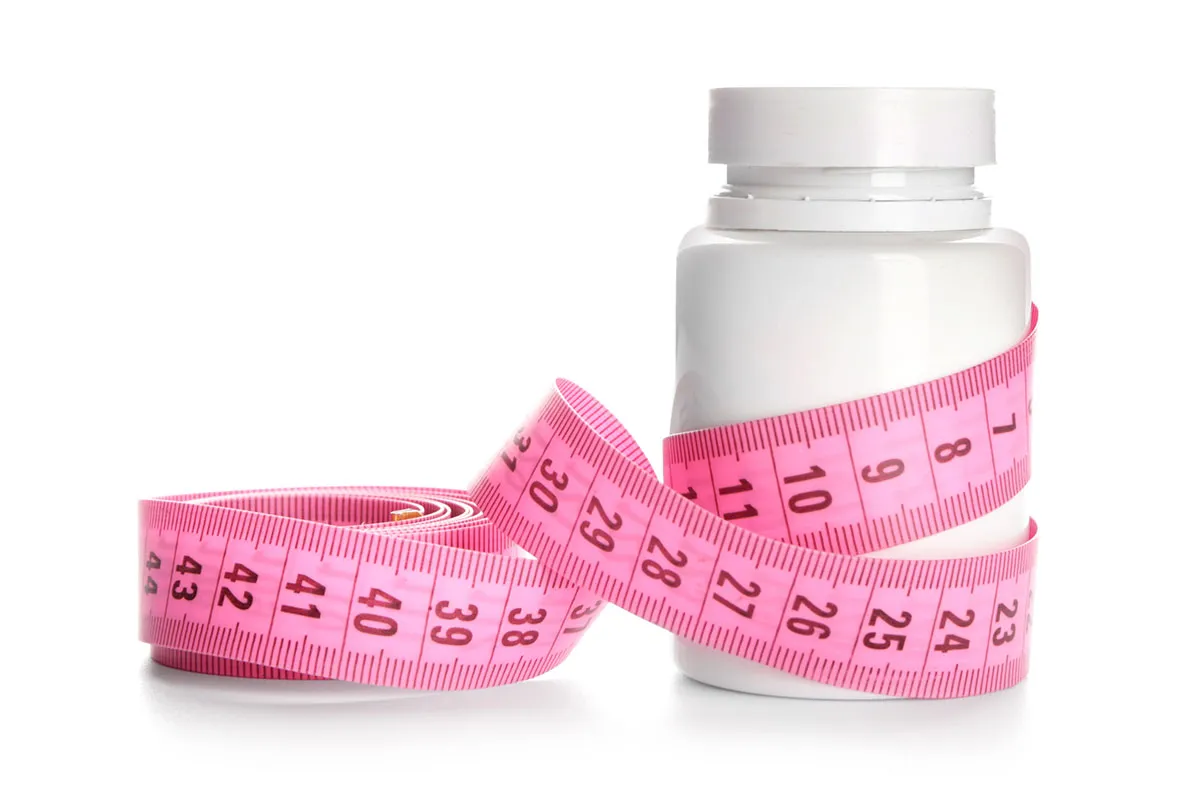 Weight loss supplements and measuring tape.