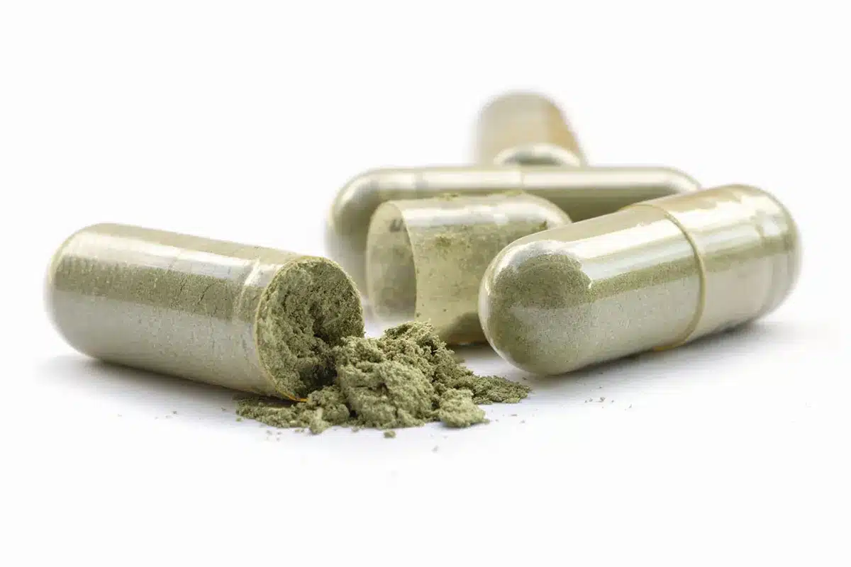 Herbal capsules spilled on white background.