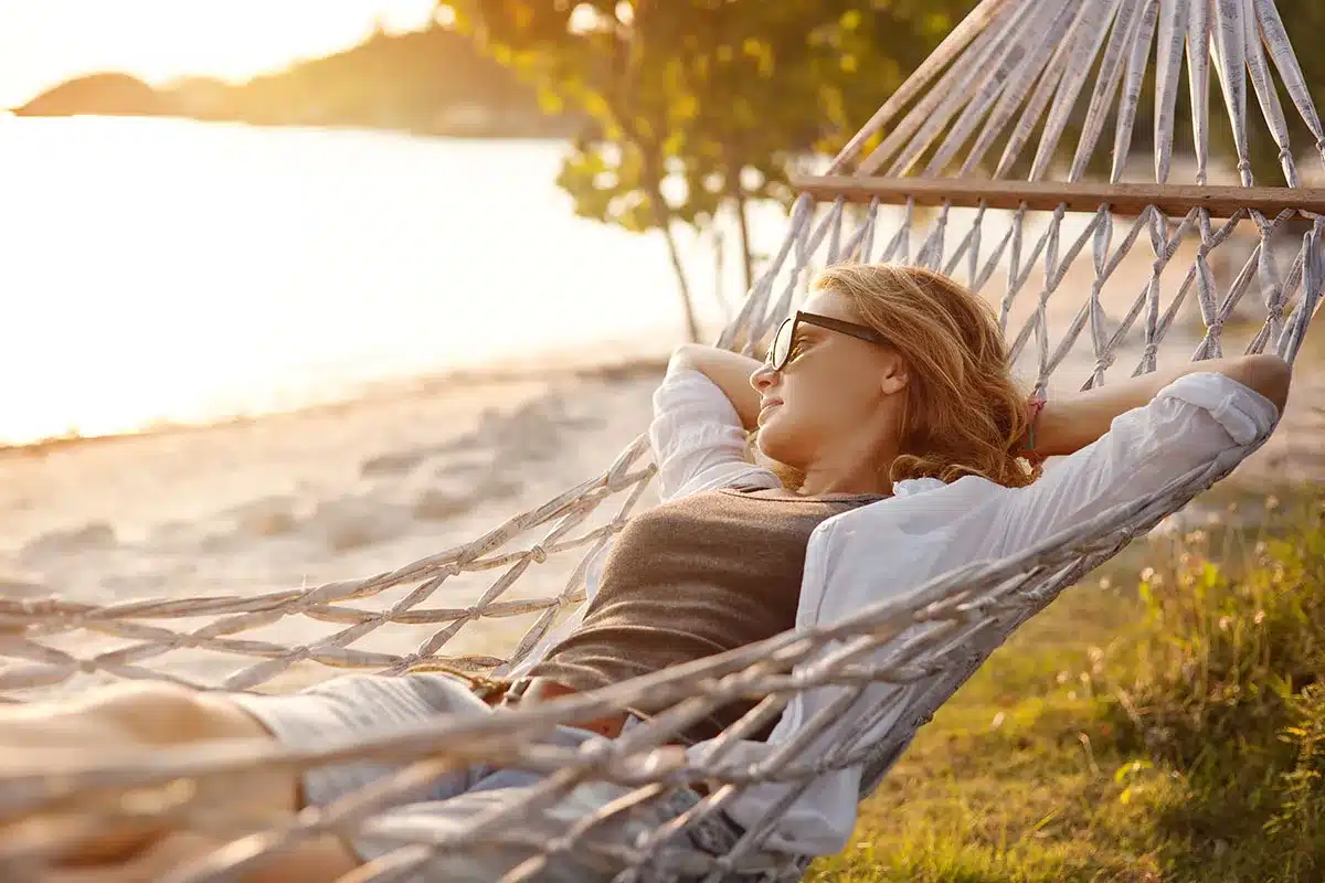 Woman relaxing in hammock by the beach.