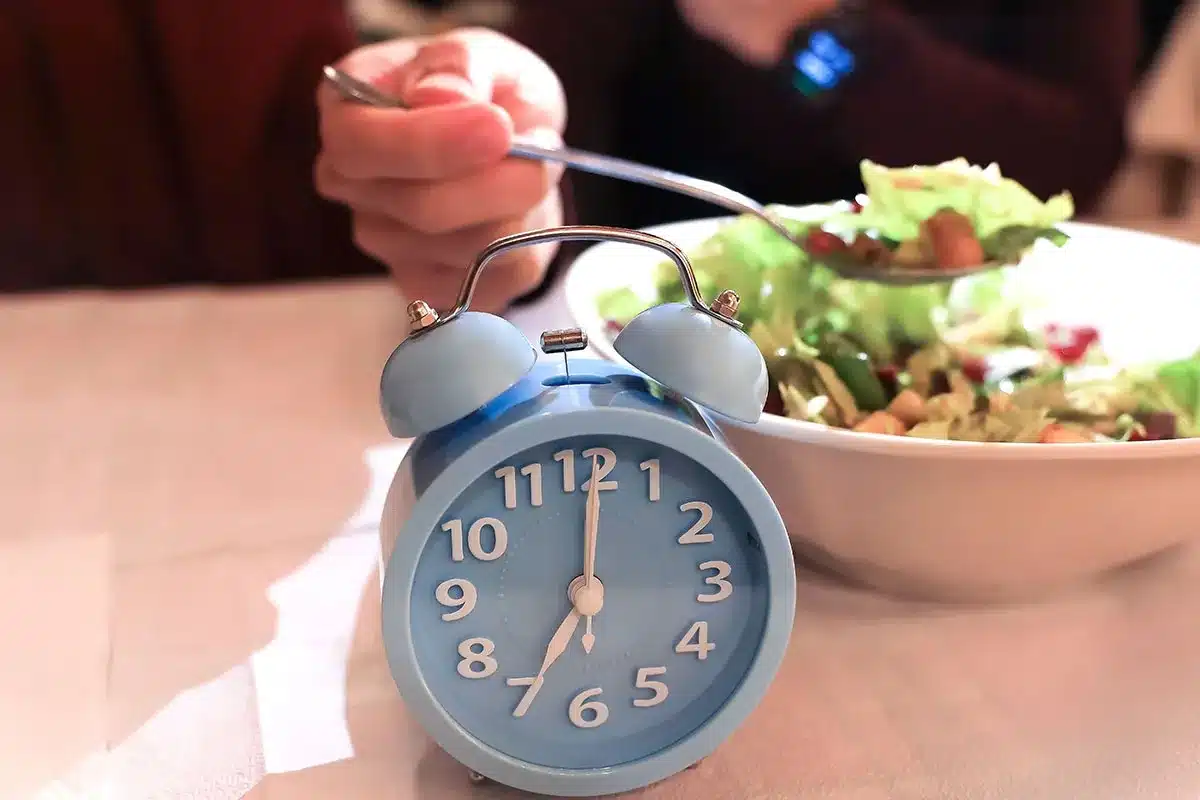 Alarm clock and healthy salad; meal timing concept.