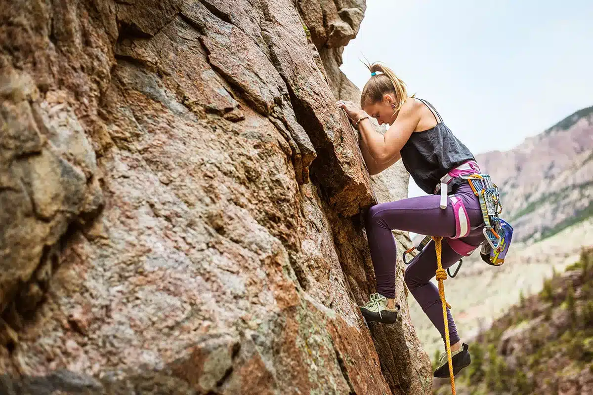 Woman rock climbing a steep cliff.