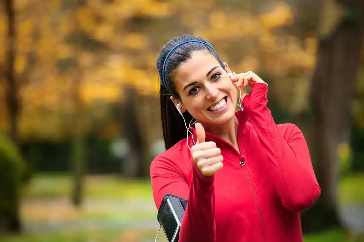 Woman jogging and giving thumbs up.