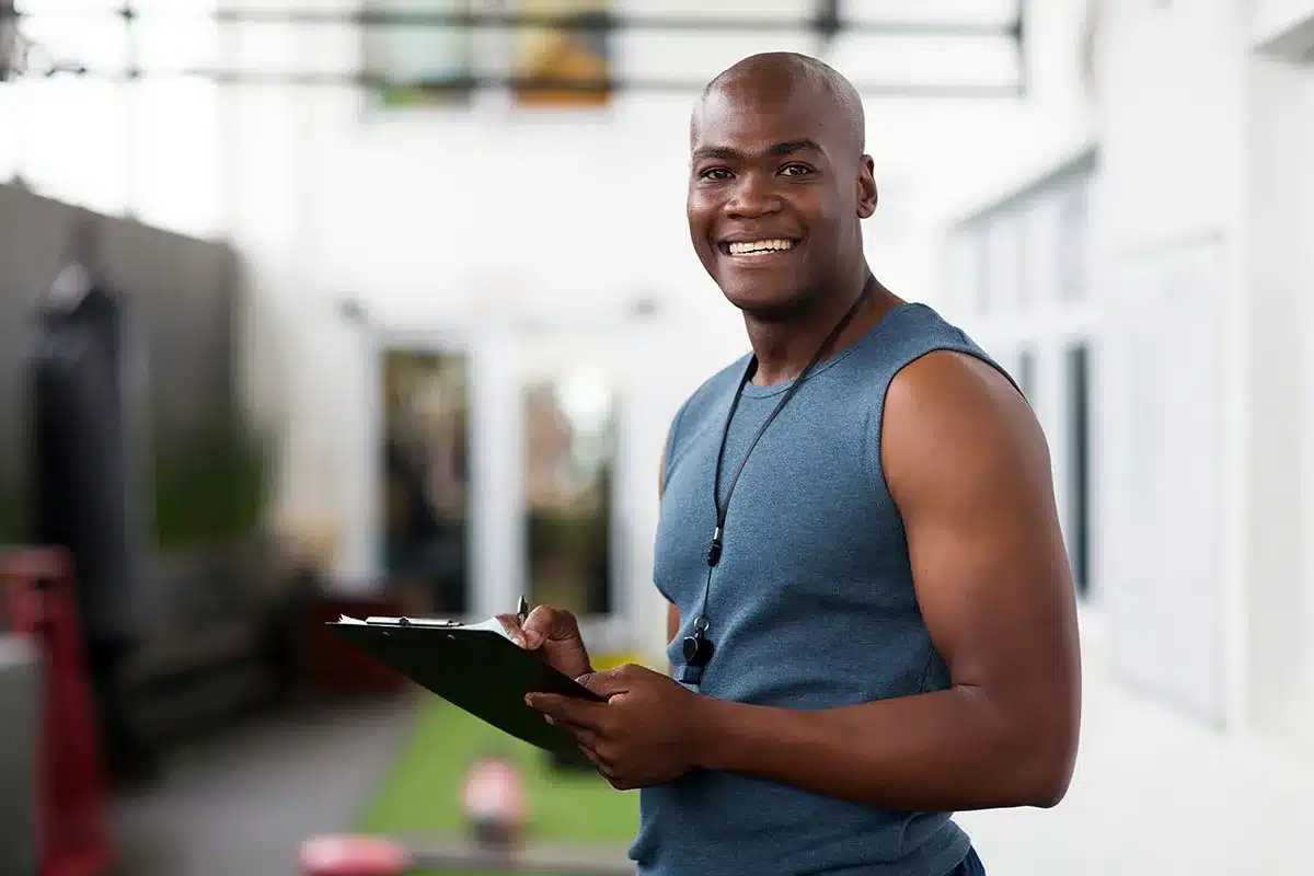 Smiling fitness trainer holding clipboard.