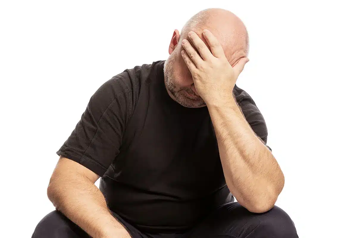 Man sitting with head in hands, looking distressed.