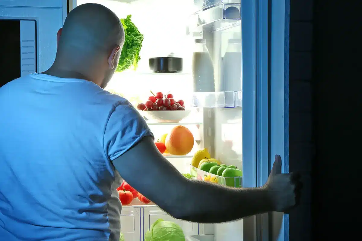 Man looking in refrigerator at night.
