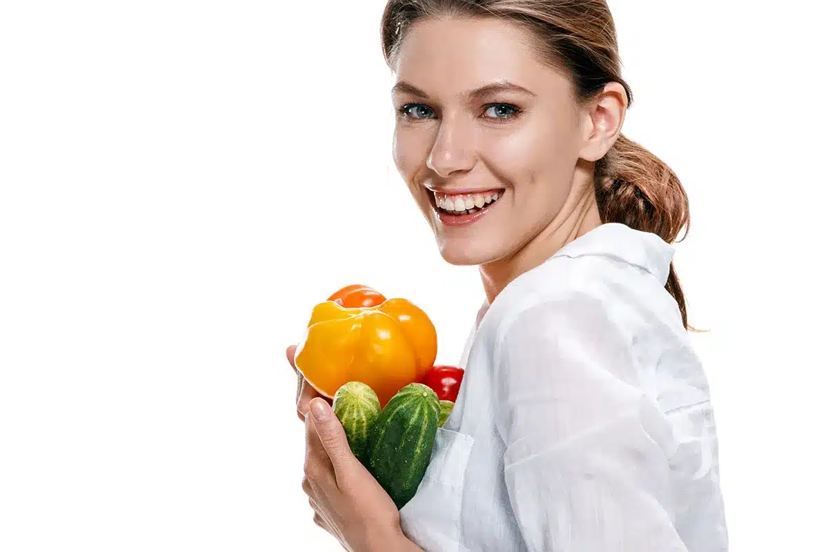 Smiling woman holding fresh vegetables.