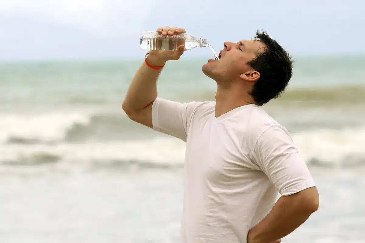 Man drinking water at the beach.