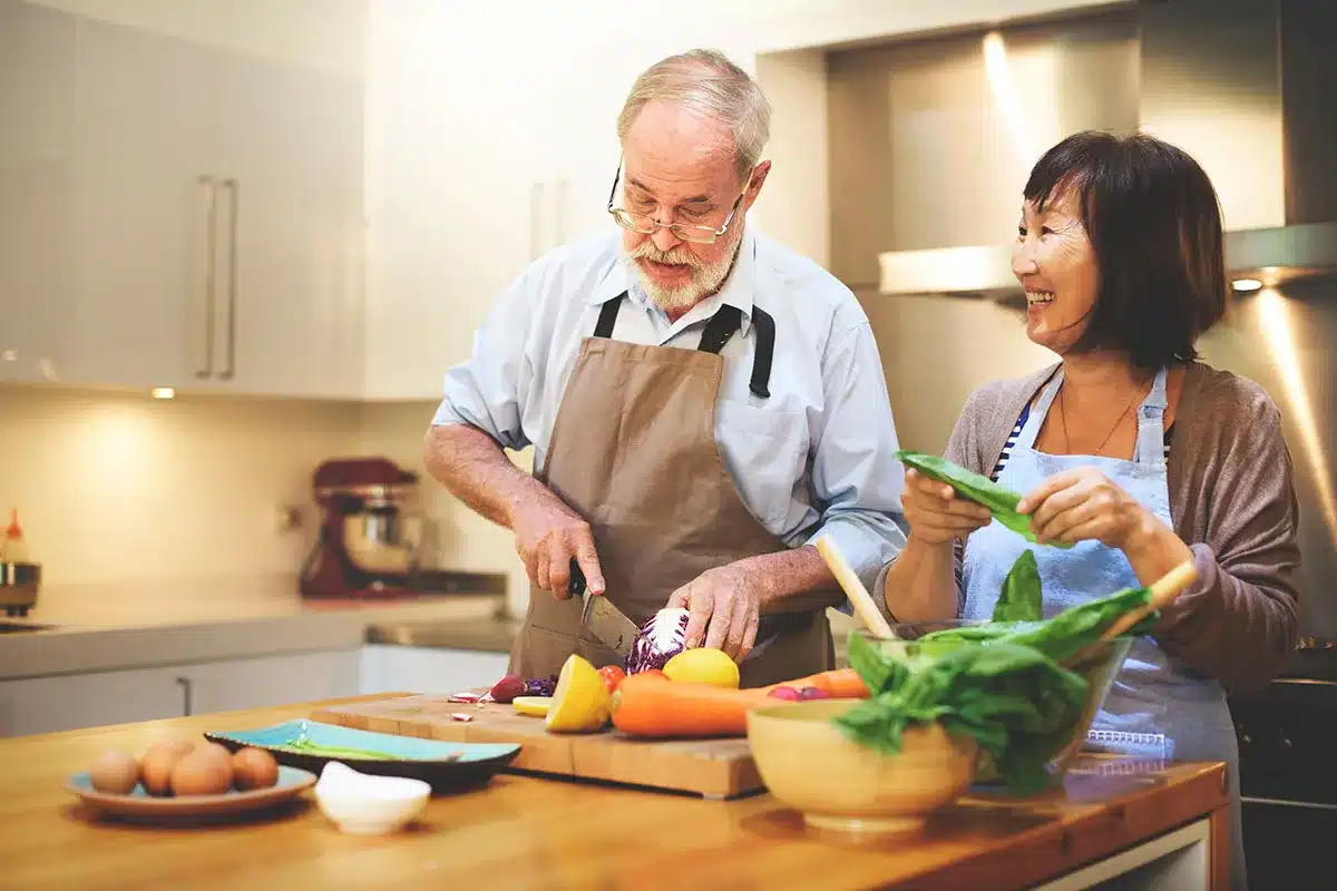 Happy senior couple cooking together in kitchen.