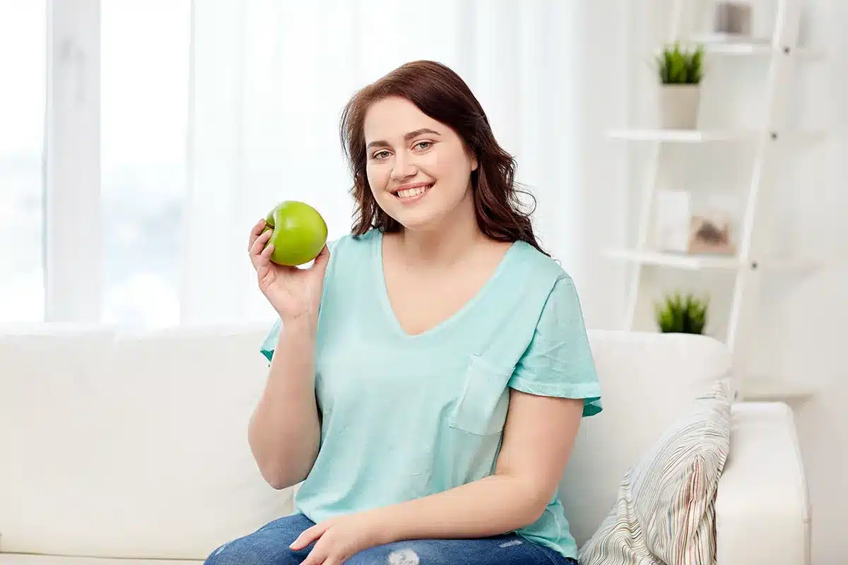 Smiling woman holding a green apple.