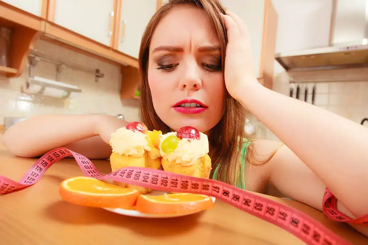 woman looking at cupcakes with measuring tape.