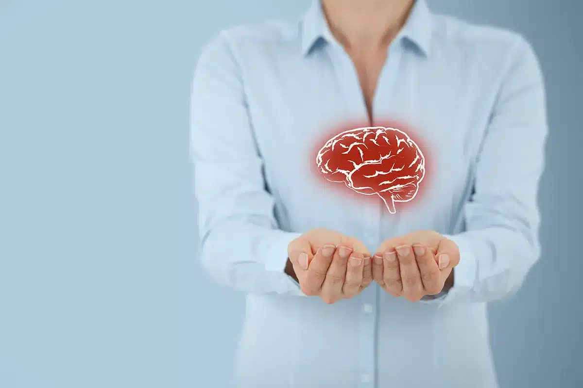 Woman's hands holding a brain graphic.