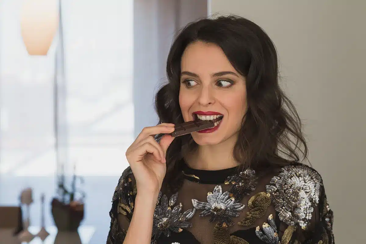 Woman eating a piece of chocolate.