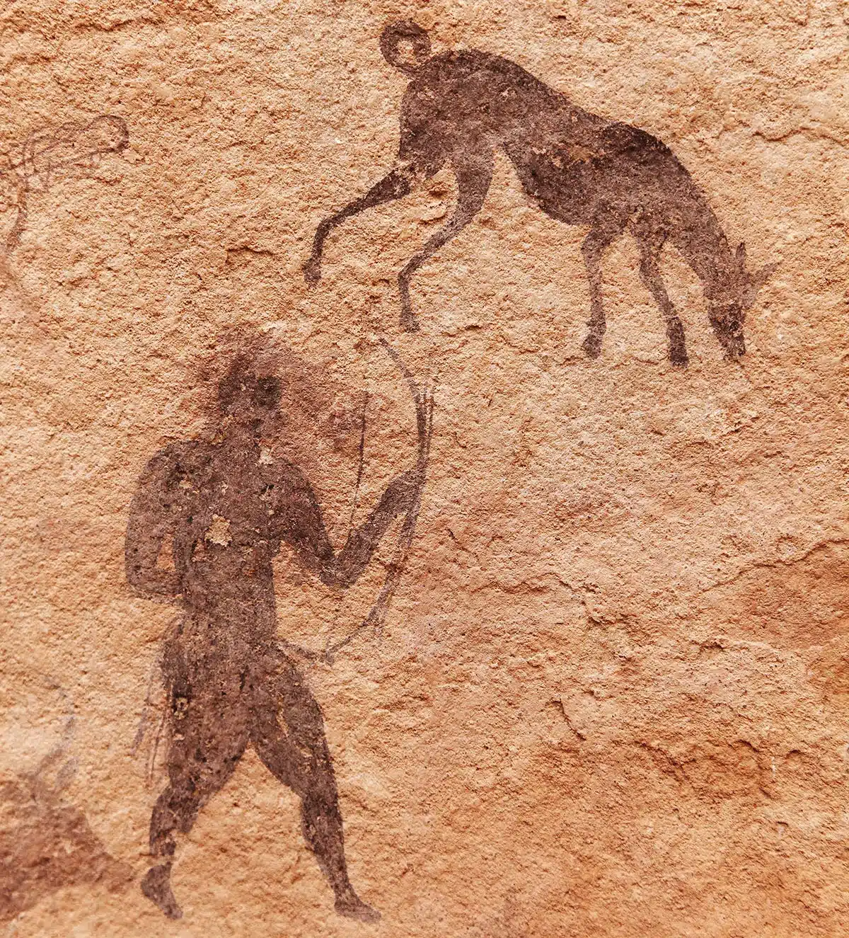 Ancient cave painting of hunter and animal.