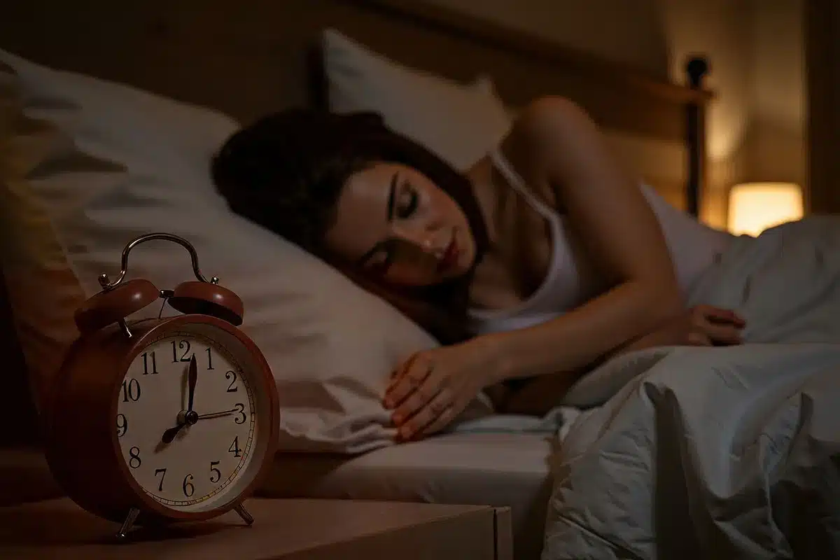 Woman sleeping soundly next to alarm clock.