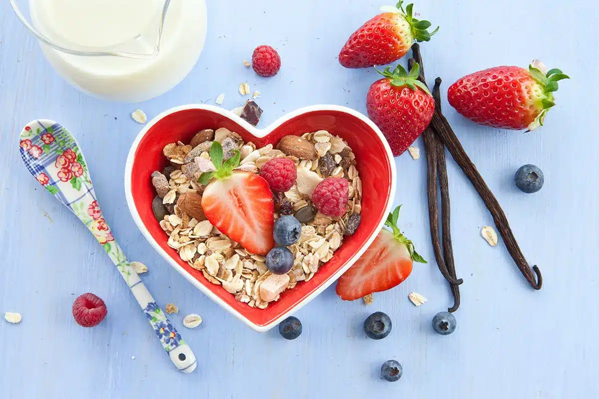 Heart-shaped bowl of muesli and berries.