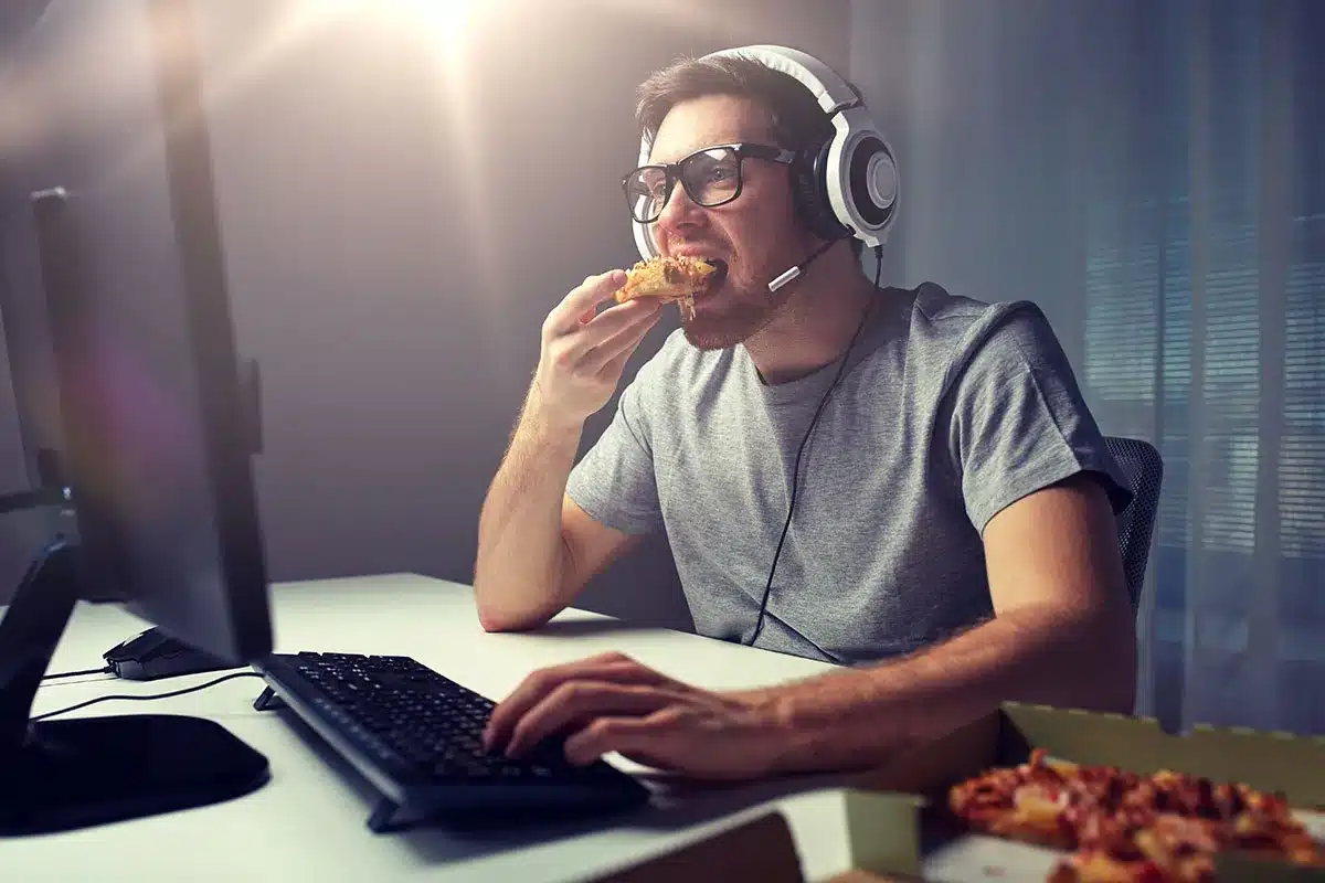 Man playing video games and eating pizza.