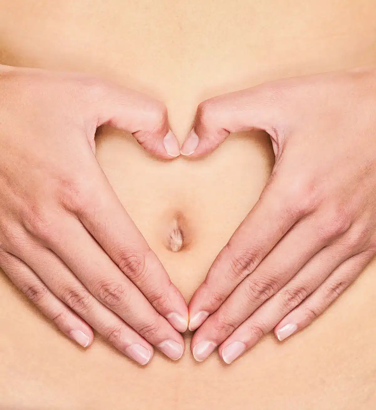 Hands forming heart shape on belly.
