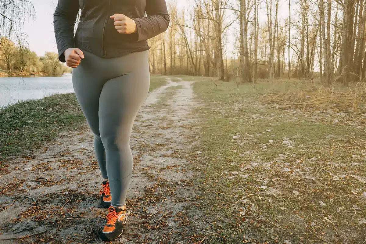 Plus-size woman jogging outdoors.