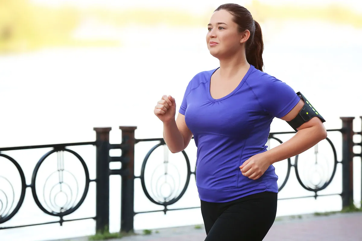 Plus-size woman jogging outdoors.
