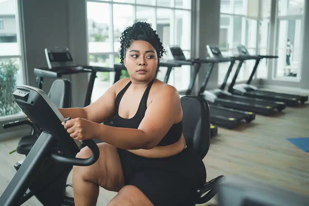 Plus-size woman exercising on stationary bike.