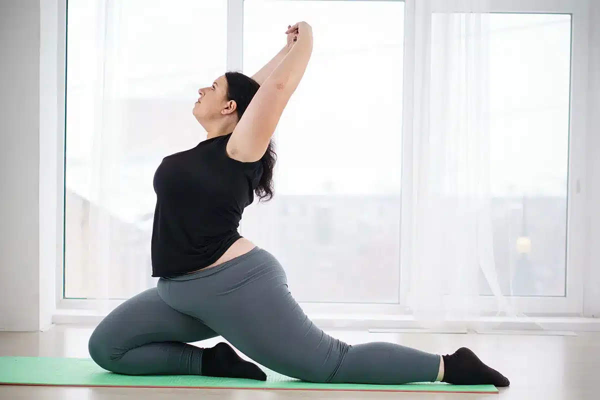 Plus-size woman doing yoga stretch.