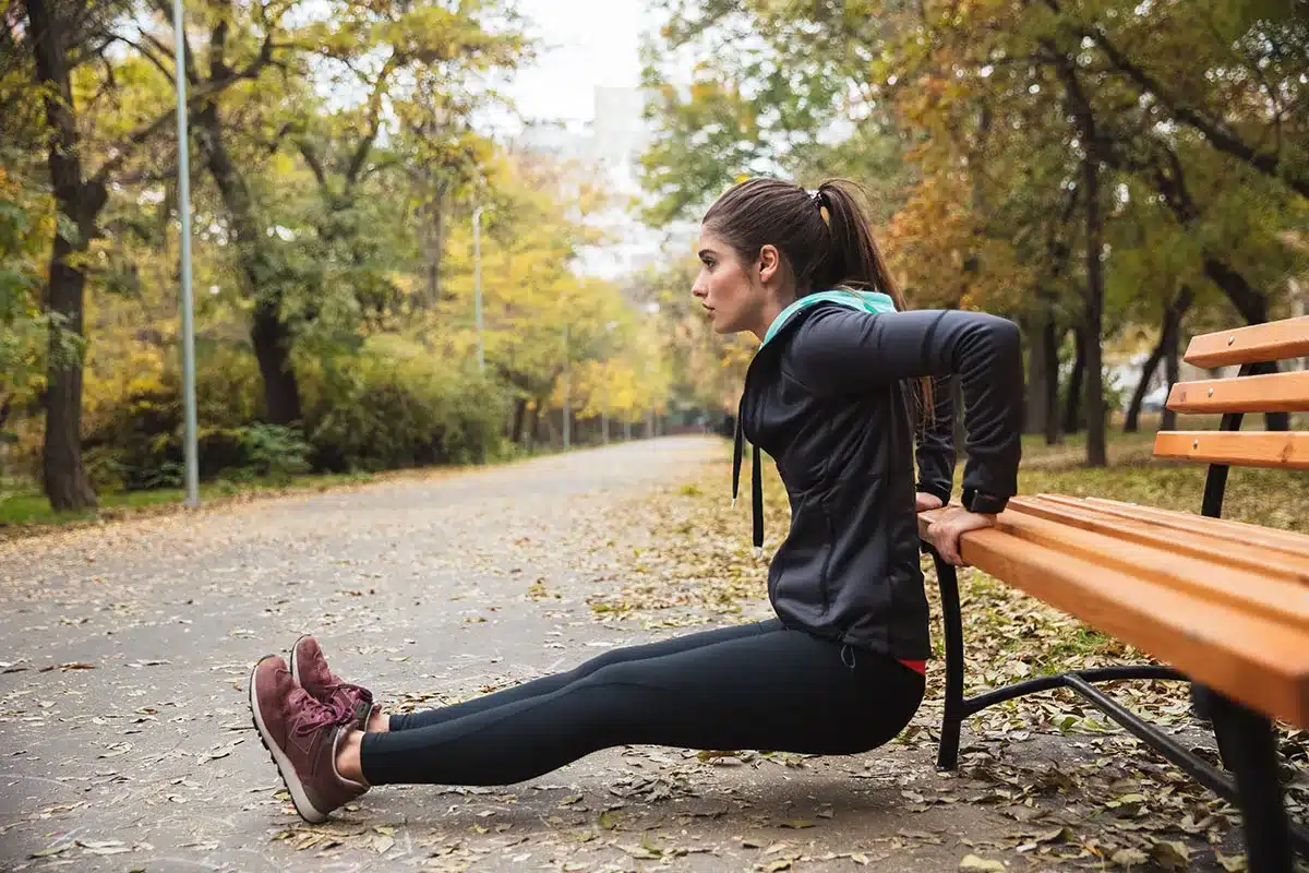 Woman doing bench dips outdoors.