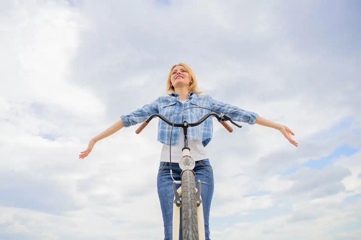 Woman joyfully riding bicycle outdoors.