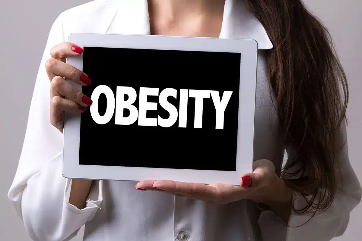 Woman holding tablet with "Obesity" text.